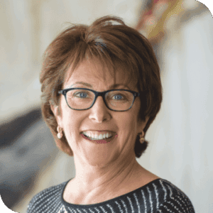 A Smiling woman with glasses and short hair.